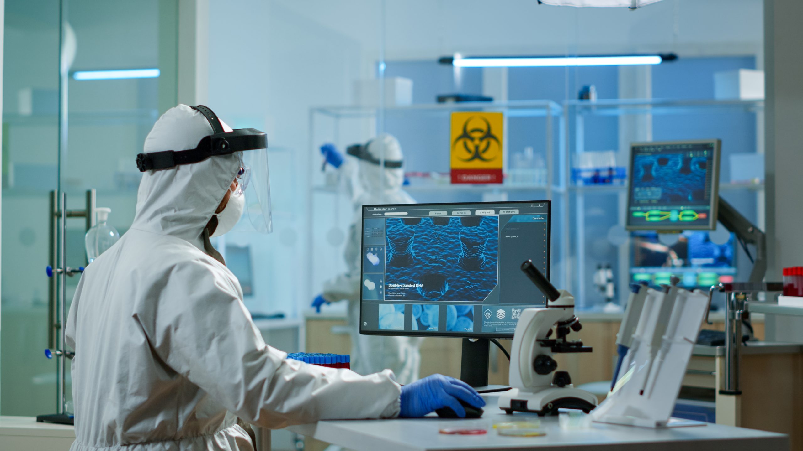 Investigador con traje de protección frente a un monitor en un laboratorio